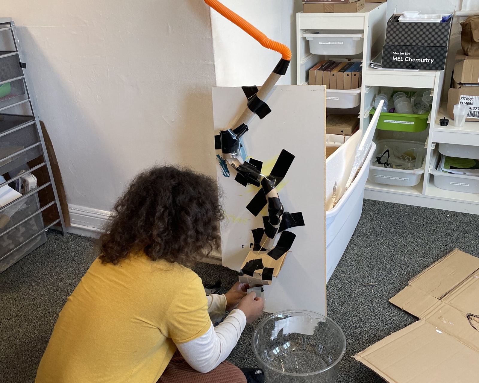 A student building a taped marble-run ramp during an engineering class
