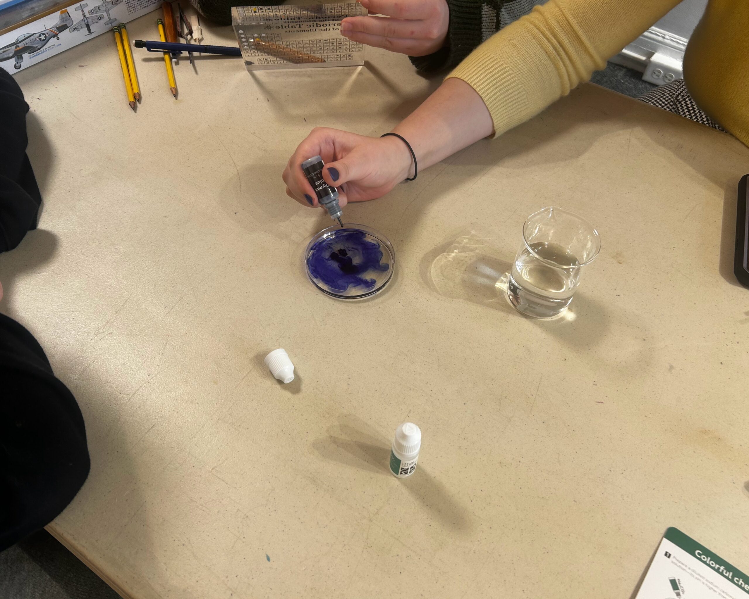 A student adding drops of indicator to a petri dish during a chemistry class